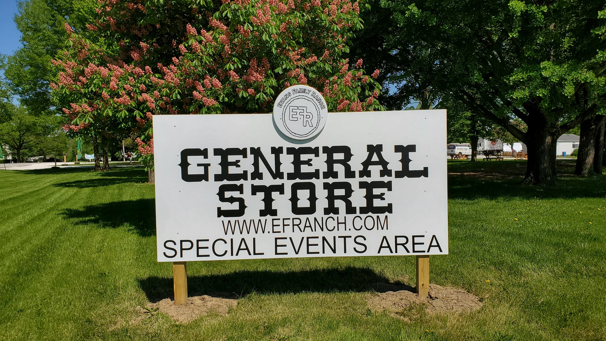 Sign for General Store at Evans Family Ranch. White Sign with Black Letters on a background of green grass and trees