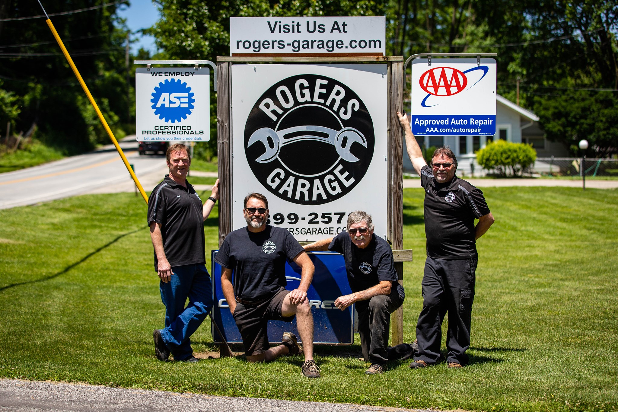 Four men standng near a Rogers Garage sign in black shirts and jeans. 